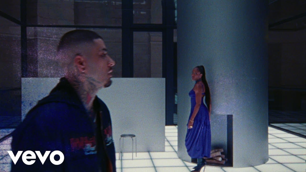 ZAYN in profile in the foreground and Ayra Starr in a long blue dress beside a grey pillar, in a bright room with a glowing tiled floor, in the 'Heaven Baby' music video