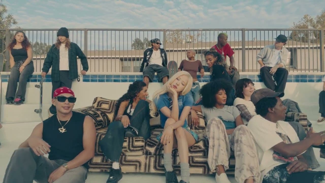 ROSÉ 'new trick' MV capture: ROSÉ sits on a sofa in an empty swimming pool surrounded by a group of friends