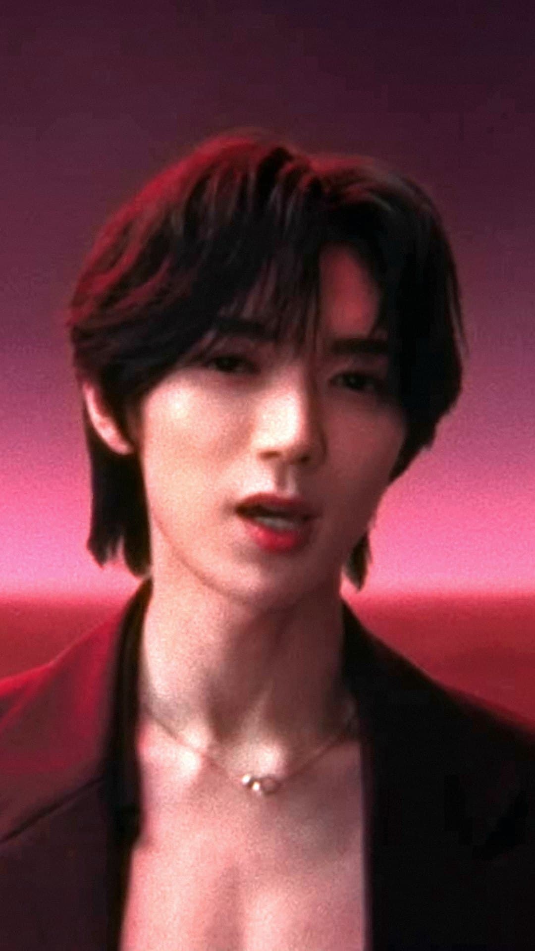 A member of Travis Japan in a dark red jacket and a thin necklace, close up against a pink and red sky in the 'EGO' music video