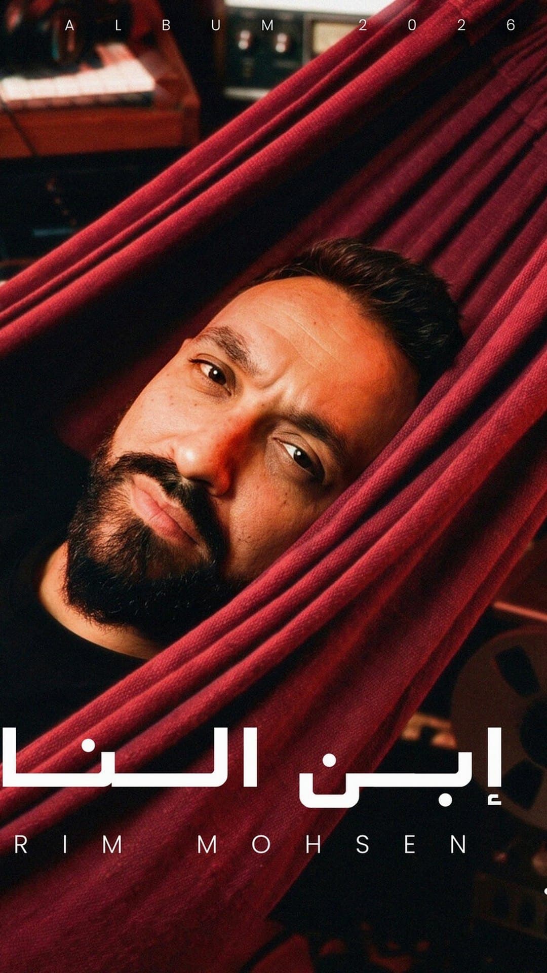 Karim Mohsen lies in a red hammock in a studio full of keyboards on the cover of his album 'Ibn El Nas'